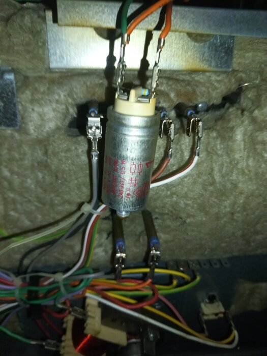 Kondensator monterad på kylplåt med anslutna kablar bakom bakre plåten.