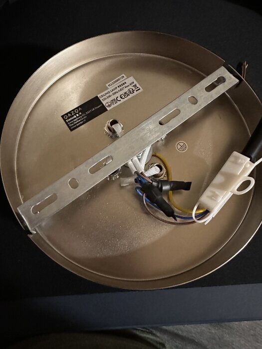 Baksidan av en taklampa med monteringsfäste och kopplingskablar, förberedd för installation i taket.