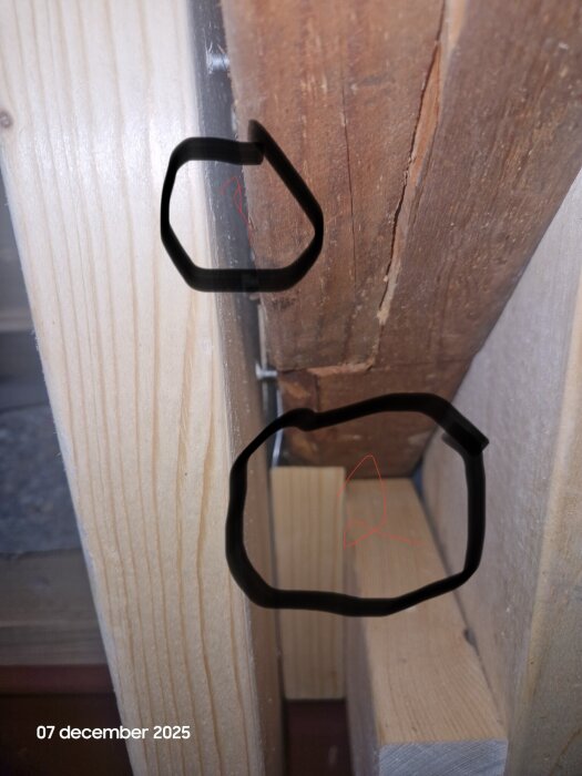 Träkonstruktion med två cirkulerade områden, ett visar en glipa och det andra brädor som ligger tätt ihop; daterat 7 december 2025.