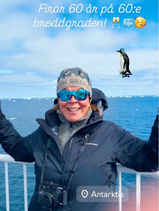 Kvinna i vinterkläder på båt i Antarktis, skrattar med ett fotomontage av en pingvin och texten "Firar 60 år på 60:e breddgraden!