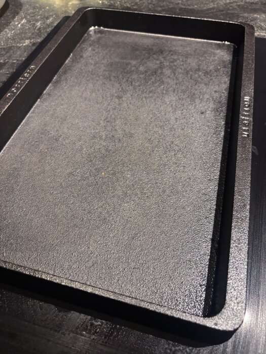 Rektangulär gjutjärnshäll efter diskning med diskborste och varmt vatten.