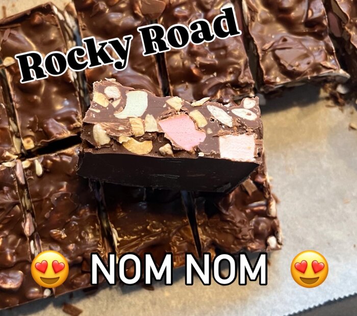 Rocky road-bitar med skumtomtar, cashewnötter, rispuffar, bilar, minimarshmallow, dumle och smält choklad, dekorerade på bakplåtspapper.