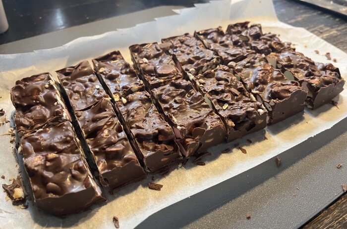 Hemmagjord Rocky Road med skumtomtar, cashewnötter, rispuffar, bilar, minimarshmallow, dumle och smält choklad, uppskuren i bitar på bakplåtspapper.