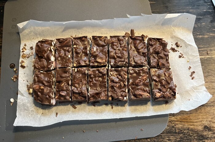 Rocky road-bitar med choklad, nötter, skumgodis, rispuffar och minimarshmallows, skurna i rutor på bakplåtspapper.