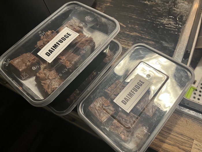 Plastlådor med hemmagjord daimfudge på ett bord, etiketter med texten "DAIMFUDGE".