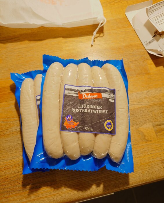 Förpackning med Thüringer Rostbratwurst från Dulano Selection på ett träbord.