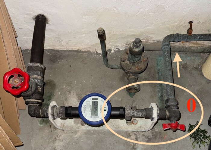 Gammalt rörsystem i källare med vattenmätare och ventiler; galvaniserade rör längs golv och vägg, en del av ett renoveringsprojekt för nybörjare.