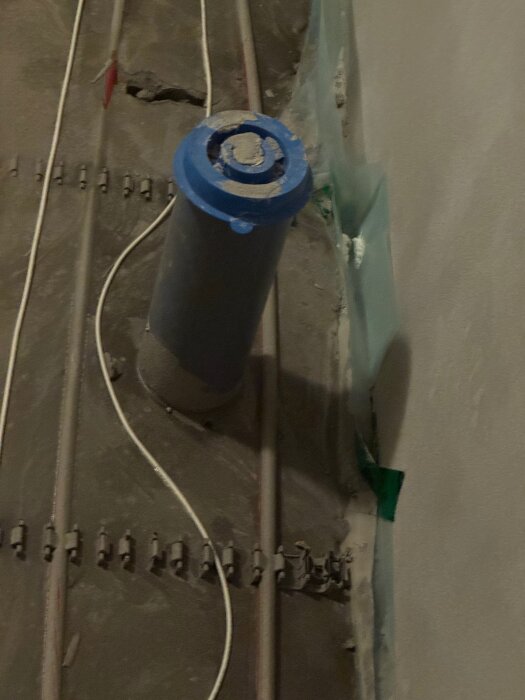 Vatten- och elrör installation i källarbadrum under renovering, rör nära golvbrunn.