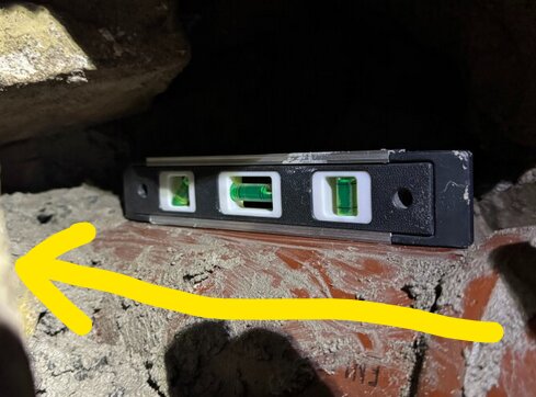 Vattenpass på avloppsrör med gul pil som pekar åt vänster, visar troligen avsaknad av korrekt fall.