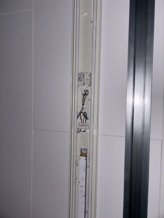 Elcentral med kablar och kopplingsbox i en vertikal panel på en vägg.