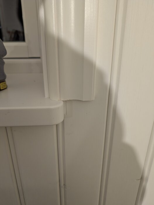 Närbild av vitt fönsterfoder där en tredjedel vilar på fönsterbrädan.
