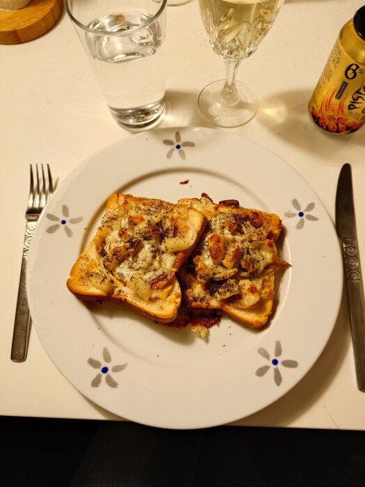 Varma mackor med ost, prosciutto, lök, tomat, ananas, majonnäs och senap på en tallrik, med dryck bredvid.
