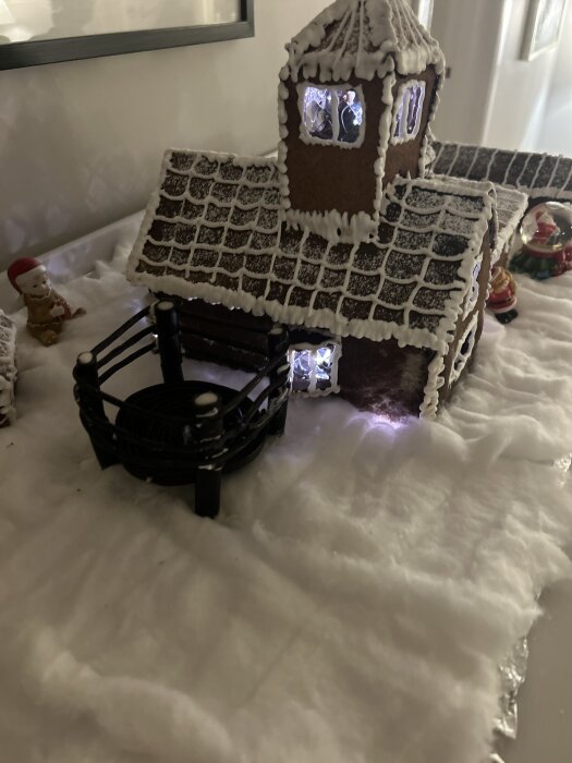 Pepparkakshus med kristyr, formad som ett hus med torn. Framför huset finns en studsmatta byggd av lakrits omgiven av snöliknande dekor.
