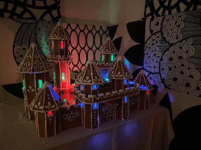 Pepparkakshus med färgglada ljusslingor på ett dekorerat bord, inspirerat av ett kreativt byggprojekt med 7,5 kg pepparkaksdeg.
