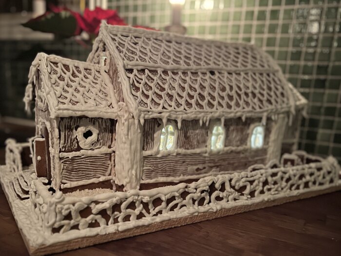 Ett pepparkakshus dekorerat med glasyr, inspirerat av Dalarö kyrka, med detaljer på tak och väggar, inrett med små fönster.