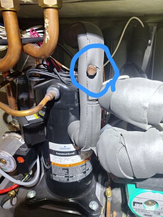 En CTC Ecoheat-värmepump med en inringad skruv på ett isolerat rör, potentiellt orsakande fukt, i en teknisk installation.