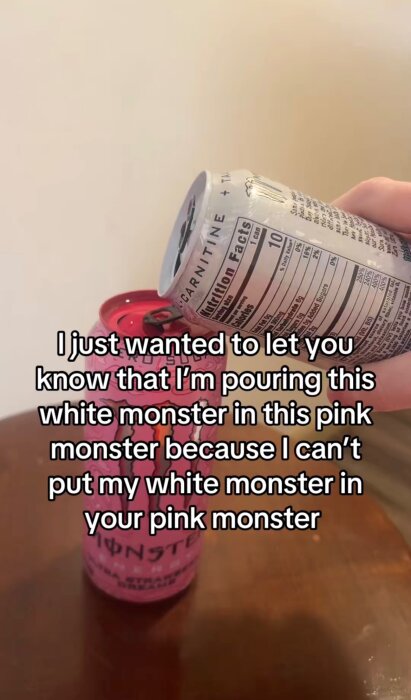Häller vit dryck från burk i en rosa Monster Energy-burk på ett bord. Texter på bilden handlar om dryck.