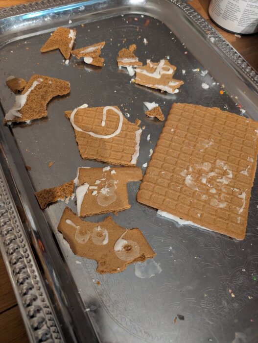Brutna bitar av ett pepparkakshus ligger på en bricka, täckta med kristyr och krossade efter att barnen lekt med det.