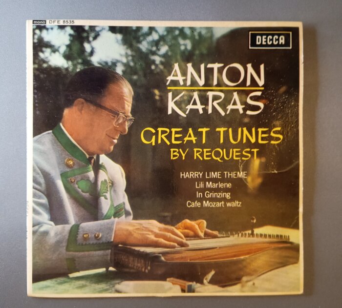 Omslag av en skiva med Anton Karas i traditionell dräkt, spelandes på ett stränginstrument, med texten "Great Tunes by Request".