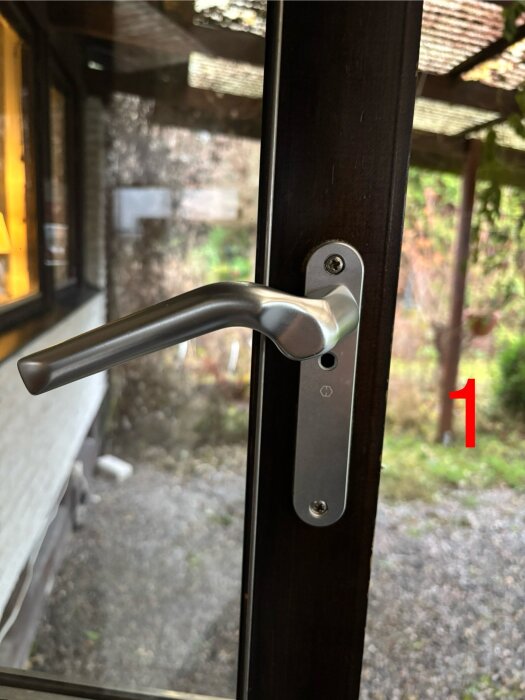 Silverfärgat handtag på altandörr med synligt skruvhål, som lätt kan öppnas utifrån. Diskussion om säkerhetslösning.