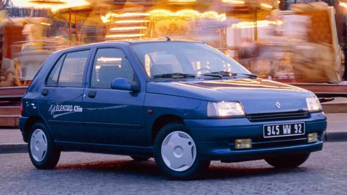 Blå Renault Clio electric parkerad framför en karusell, belysning i bakgrunden.