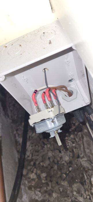 Termostat med kablar, monterad på insidan av en vit kopplingsdosa, del av felsökning av bergvärmepumpsystem med elpatron.