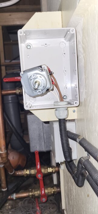 Termostat monterad i elbox med kopplingar, i ett uppvärmningssystem. Innerdelen av termostaten är synlig.