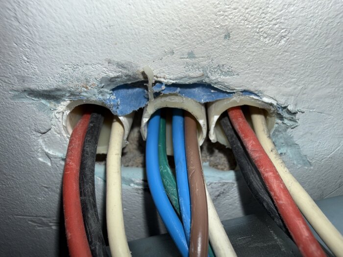 Fyra VP-rör med olika kablar; röda, svarta, vita, blå och bruna kablar syns i öppningarna i väggen.