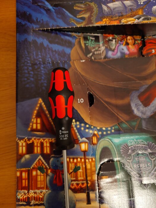 Skruvmejsel av märket Wera framför en julkalender med julmotiv, inklusive snögubbe och dekorerade hus.