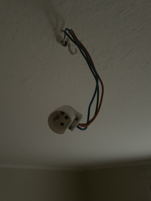 Takmonterad lite ojordad lamputtag med synliga kablar.