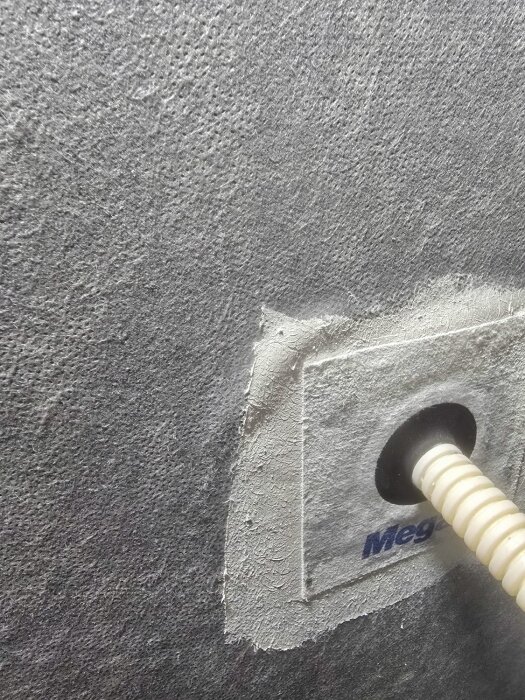 Våtrumsfolie på badrumsvägg med rörmanschett applicerad med Megarum, synliga strukturer i ytan.