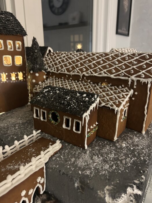 Pepparkakshus med detaljerade fönster, dekorerat med glasyr och silverkulor, utgör ett juligt bygge i form av en by.