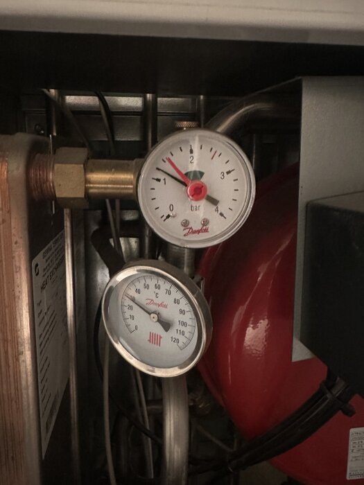 Manometer och termometer på fjärrvärmeanläggning, tryck på 1,5 bar, temperatur 70°C, indikering av tryckfall och problem med läckage från returledning.