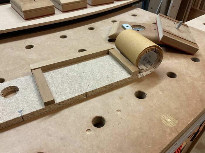 En arbetsbänk med DIY slipklossar och en rulle Bosch slippapper.