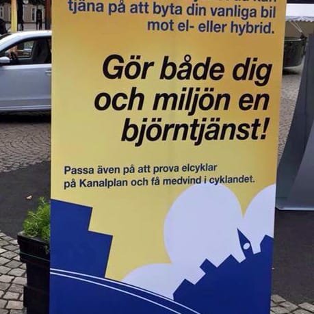 Reklamskylt med texten "Gör både dig och miljön en björntjänst!" samt erbjudande om att prova elcyklar.
