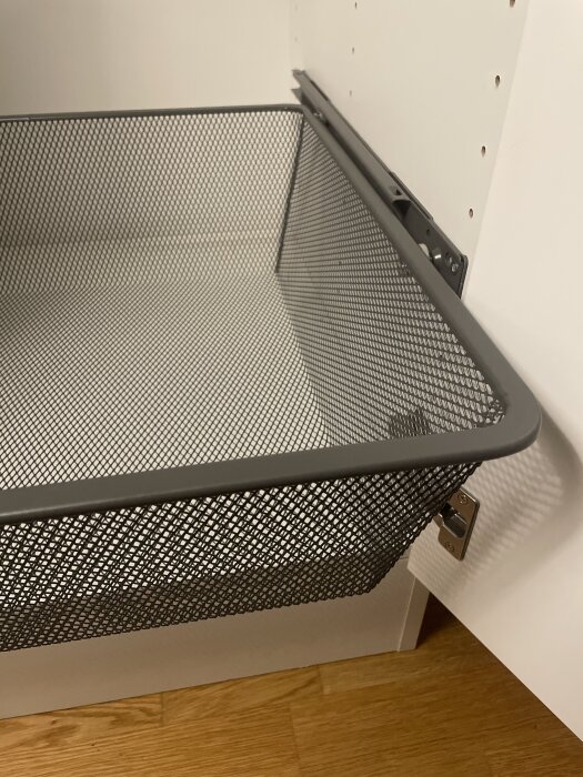 Meshback på skenor installerad i en Vedum-garderob, antracitfärg, mot en vit bakgrund och trägolv.