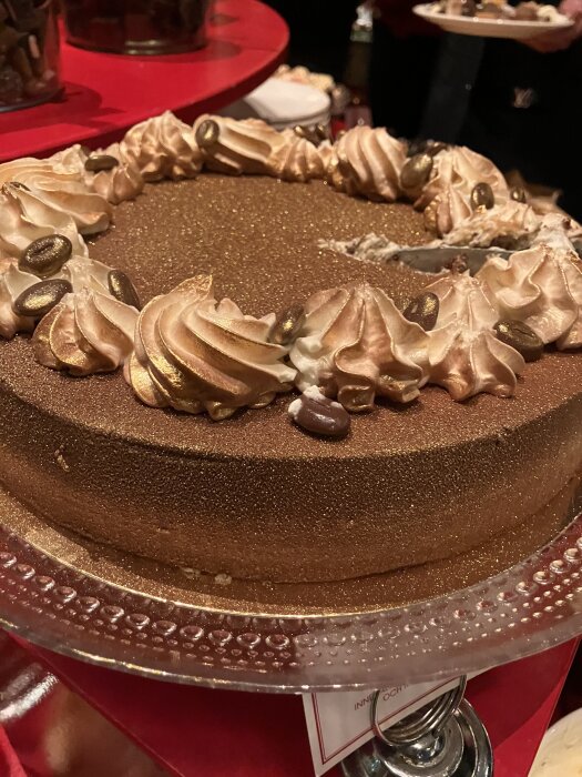 En guldig tårta dekorerad med kräm och chokladbönor på ett julbord.