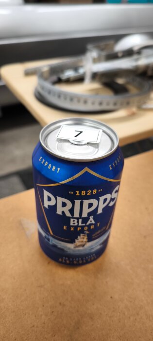 Blå Pripps Blå ölburk på ett bord med en etikett som visar siffran 7.