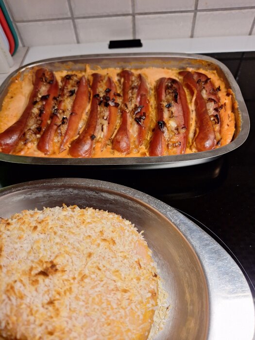 Grillkorvar med lök och sås i ugnsform samt en griljerad julskinka på diskbänk.