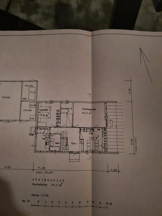 Ritning över våningsplan med kök, vardagsrum, sovrum och garage, skala 1:100.