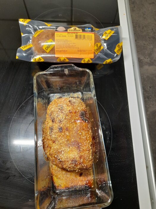 Liten julskinka bakad i glasform med paket från SP Chark liggande ovanpå spisen.