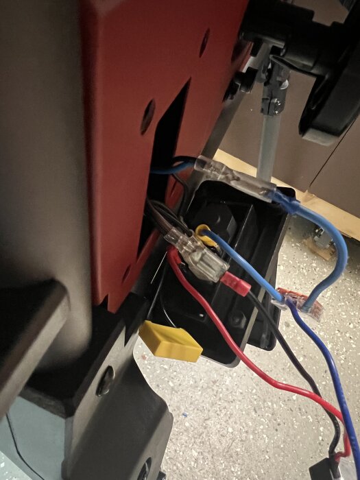 Elektriska kablar anslutna till en panel i en konstruktion, visande blå och röda ledningar kopplade med anslutningar.