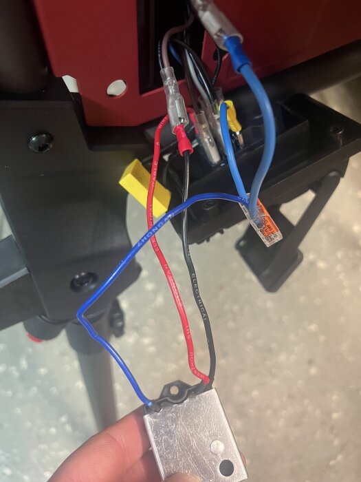 Färgade elektriska kablar kopplade till en metallbox, del av byggprojekt.