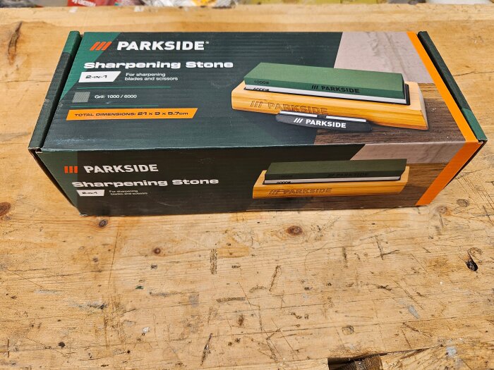Kartong med Parkside Slipsten 1000/6000 grus för knivar och verktyg, placerad på ett träbord.