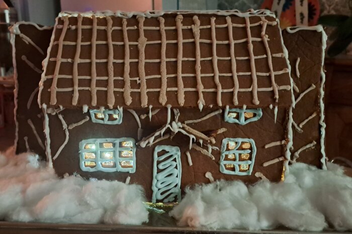 Pepparkakshus dekorerat med kristyr, föreställande Rosehill Cottage från filmen "The Holiday", omgivet av bomull som ser ut som snö.