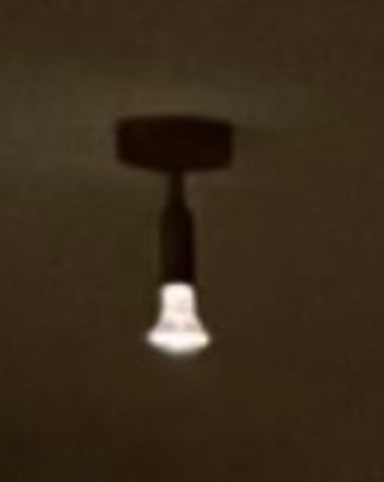 En fast installerad spotlight taklampa som lyser i ett mörkt rum.