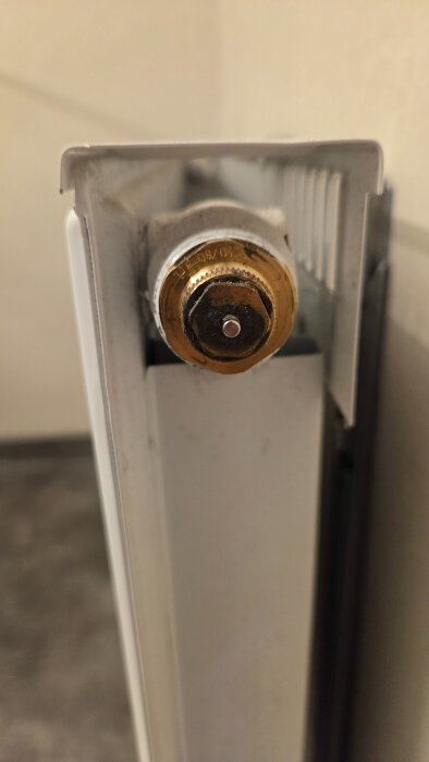 Närbild på gammal termostatventil på en radiator, som behöver en specifik adapter för ny termostatanslutning.