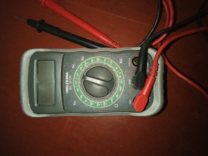 En digital multimeter från märket Biltema med avläsningspanel och sladdar placerad på ett bord.