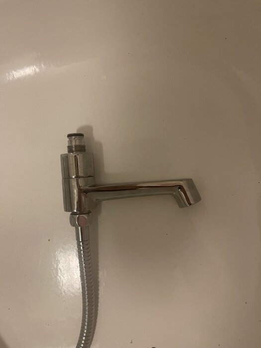 Lös pip från IKEA Brogrund duschblandare med slitna gängor, placerad på vit bakgrund. En ledning är fäst längst ned på pipen.