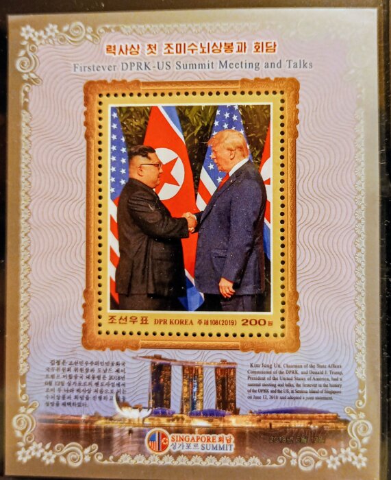 Frimärke från Nordkorea som visar ett möte mellan två ledare, med texten "Firstever DPRK-US Summit Meeting and Talks" och båda nationernas flaggor.